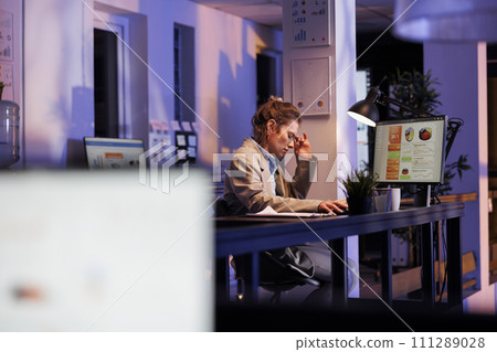 Tired corporate employee working overhours at marketing project, analyzing financial graphs report in startup office. Exhausted businesswoman planning investment strategy to increase company profit Tired corporate employee working overhours at marketing project, analyzing financial graphs report in startup office. Exhausted businesswoman planning investment strategy to increase company profit 111289028
