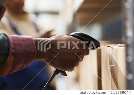 African american storehouse employee arm using barcode scanner on cardboard box. Warehouse operator hand checking merchandise carton bar code, holding digital scanning equipment close up 111289044