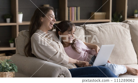 Woman and daughter spend weekend watching comedy movies using laptop Woman and daughter spend weekend watching comedy movies using laptop 111289062
