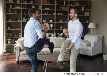 Carefree young brothers dancing in modern living room 111290190