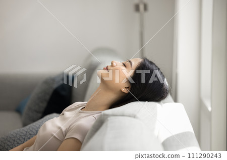 Peaceful relaxed beautiful 20s Asian girl resting on couch Peaceful relaxed beautiful 20s Asian girl resting on couch 111290243