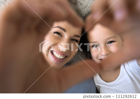 Cute little daughter and loving mom showing symbol of love 111292612