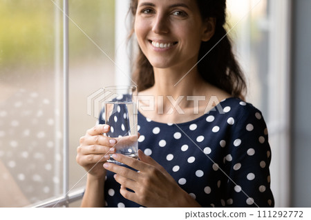 Close up smiling woman holding glass of pure fresh water Close up smiling woman holding glass of pure fresh water 111292772
