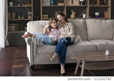 Mother have friendly conversation with little daughter sitting on sofa Mother have friendly conversation with little daughter sitting on sofa 111292792