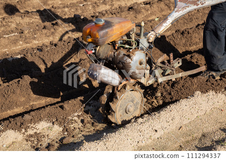 Farmer using motorized cultivator on the field 111294337