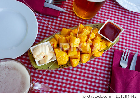 Spanish cuisine patatas bravas served with sauce on plate on wooden table Spanish cuisine patatas bravas served with sauce on plate on wooden table 111294442