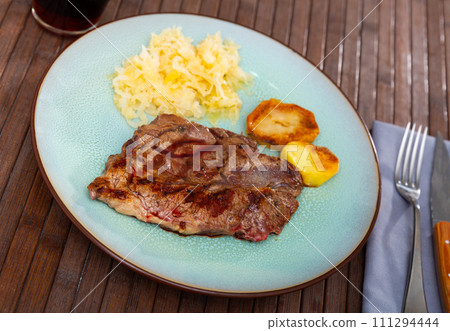 Grilled beef piece, potatoes and sauerkraut served in a plate Grilled beef piece, potatoes and sauerkraut served in a plate 111294444