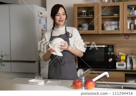 Young woman wiping dishes in the kitchen 111294454