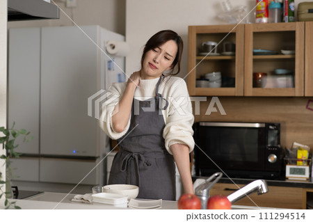 Young woman with shoulder pain in the kitchen Young woman with shoulder pain in the kitchen 111294514