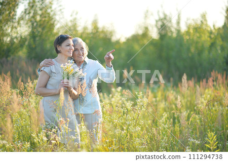 mom and daughter with flowers in the field 111294738