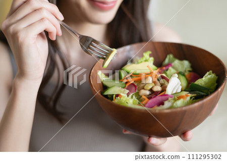 Hand of a young woman eating salad Hand of a young woman eating salad 111295302