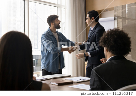 Happy young Arab business partners shaking hands at team meeting Happy young Arab business partners shaking hands at team meeting 111295317