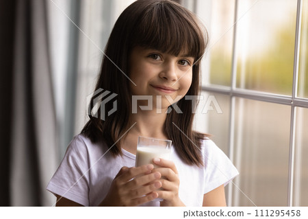 Happy preteen girl stand by window hold glass of milk 111295458