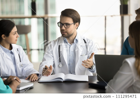 Serious male chief doctor in glasses speaking at meeting Serious male chief doctor in glasses speaking at meeting 111295471