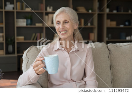 Middle-aged woman relax on sofa with cup of tea Middle-aged woman relax on sofa with cup of tea 111295472