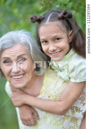Portrait of happy grandmother and granddaughter in park 111295564