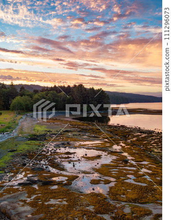 View of Rocky shore on Pacific Ocean West Coast during Dramatic Sunset. 111296073