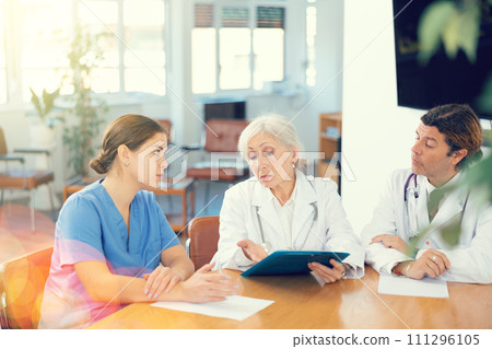 Senior female head doctor conducting medical council with colleagues Senior female head doctor conducting medical council with colleagues 111296105