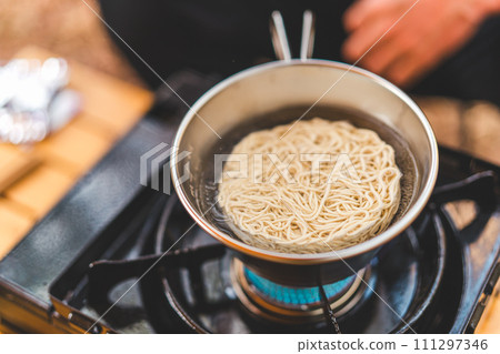 Camper man eating instant ramen/bagged noodles at camp meal Camper man eating instant ramen/bagged noodles at camp meal 111297346