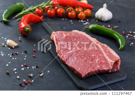 Raw fresh marbled meat and seasonings on dark background Raw fresh marbled meat and seasonings on dark background 111297467