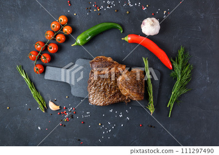 Grilled beef steak ribeye rare on on dark background top view Grilled beef steak ribeye rare on on dark background top view 111297490