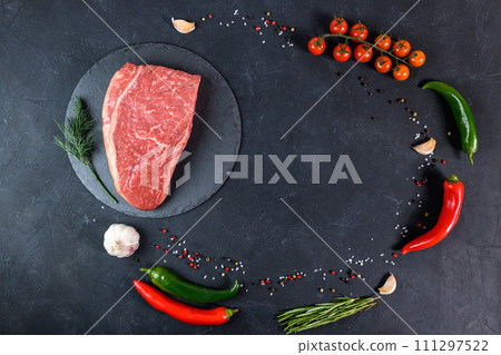 Raw fresh marbled meat and seasonings on dark background top view Raw fresh marbled meat and seasonings on dark background top view 111297522