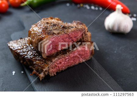 Grilled beef steak ribeye rare on on dark background Grilled beef steak ribeye rare on on dark background 111297563
