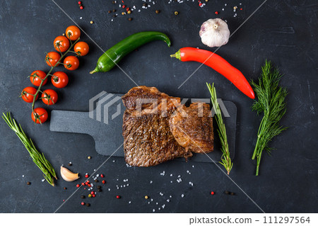 Grilled beef steak ribeye rare on on dark background top view Grilled beef steak ribeye rare on on dark background top view 111297564