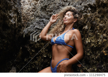 Beautiful body woman in bikini standing by a rock. Sexy girl 111298475