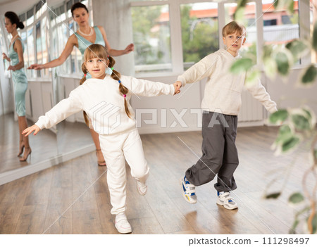 Smiling preteen girl practicing vigorous dance with boy in choreography studio 111298497