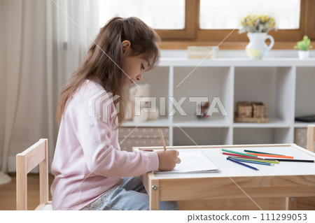 Little girl drawing pictures sit on chair at table 111299053
