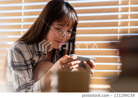 A young woman watching a video on her smartphone A young woman watching a video on her smartphone 111299139