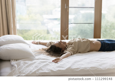 Young happy woman fell down on bed with arms raised Young happy woman fell down on bed with arms raised 111299148