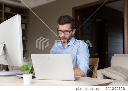Freelancer working seated at desk with pc monitor and laptop Freelancer working seated at desk with pc monitor and laptop 111299150