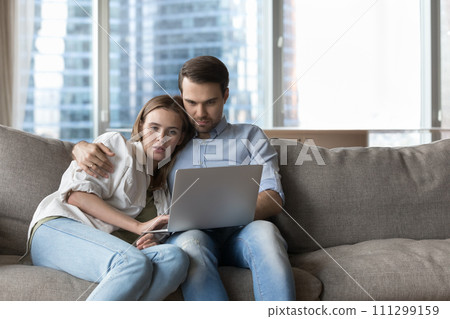 Millennial loving couple buying on internet using laptop Millennial loving couple buying on internet using laptop 111299159