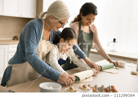 Happy blonde grandmother training little grandchild and daughter to bake Happy blonde grandmother training little grandchild and daughter to bake 111299164