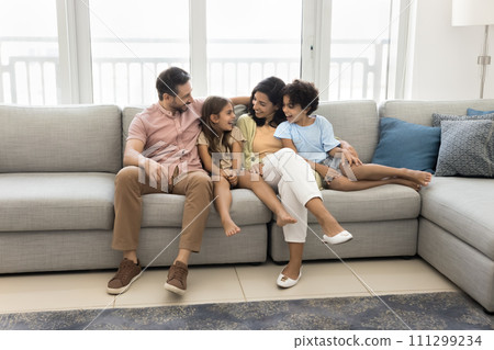 Cheerful parents and son and daughter kids resting on couch Cheerful parents and son and daughter kids resting on couch 111299234