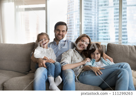 Young parents posing for photo at home with two kids 111299263