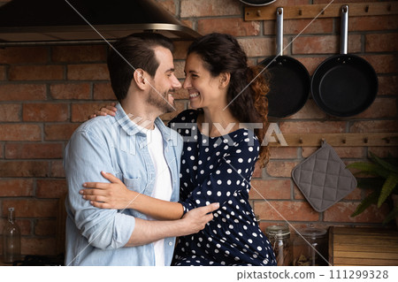 Happy loving millennial couple hugging, enjoying romantic moment in kitchen 111299328