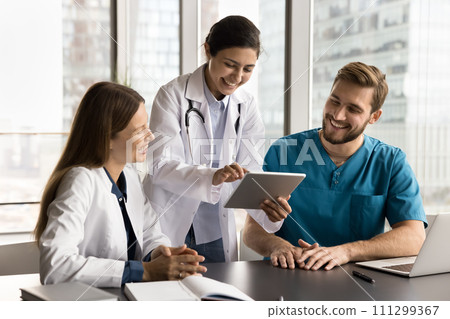 Cheerful diverse clinic medical colleagues in uniforms using tablet computer 111299367