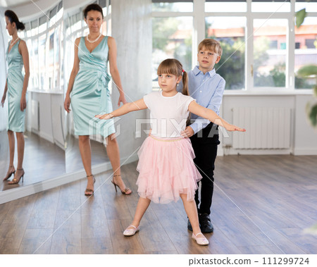 Tween girl and boy practicing waltz in dance hall with female mentor Tween girl and boy practicing waltz in dance hall with female mentor 111299724