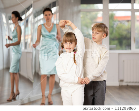 Preteen boy and girl refining slow foxtrot technique in dance hall 111299860