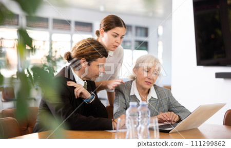 three positive office workers are sitting at table animatedly and actively discussing current work 111299862