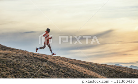 Sporty man runs in training on downhill meadow 111300436