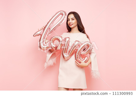 A beautiful young woman holding a balloon A beautiful young woman holding a balloon 111300993