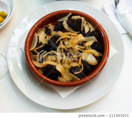 Delicious Catalan blood sausages with grilled onion served on plate. Morcilla con cebolla Delicious Catalan blood sausages with grilled onion served on plate. Morcilla con cebolla 111301031