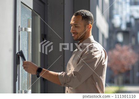 Side view of hispanic unshaved male opening entrance door with contactless plastic key card. Contemporary office worker electronic sensor for accessing building area only for authorized people. 111301110
