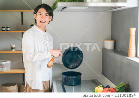 一個年輕人在廚房裡用小火煮燉菜 111301854