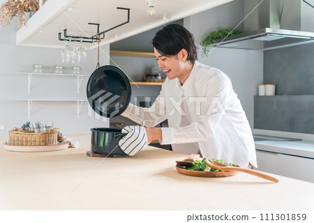 一個年輕人在廚房打開鍋蓋(烹飪課/家庭烹飪/烹飪男孩) 一個年輕人在廚房打開鍋蓋(烹飪課/家庭烹飪/烹飪男孩) 111301859