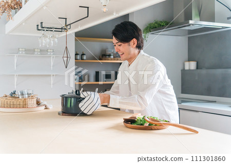 一個年輕人在廚房裡用鍋子做飯(烹飪課、招待、家庭烹飪、烹飪男孩) 一個年輕人在廚房裡用鍋子做飯(烹飪課、招待、家庭烹飪、烹飪男孩) 111301860